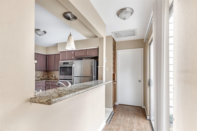 kitchen featuring light hardwood / wood-style flooring, appliances with stainless steel finishes, tasteful backsplash, dark brown cabinets, and kitchen peninsula