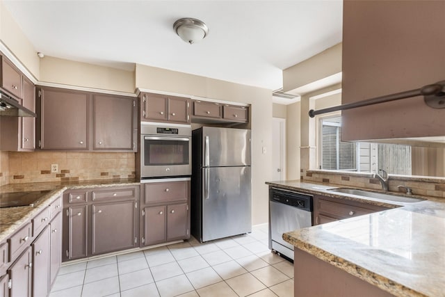 kitchen featuring dark brown cabinetry, sink, stainless steel appliances, tasteful backsplash, and light tile patterned floors