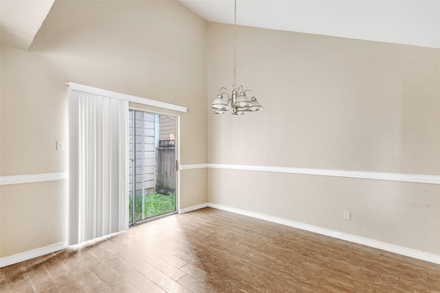 unfurnished room with hardwood / wood-style floors, vaulted ceiling, and a notable chandelier