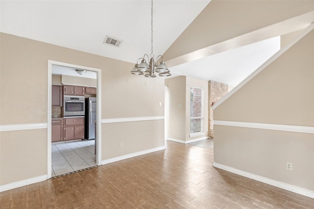 unfurnished dining area with a chandelier, lofted ceiling, and light wood-type flooring