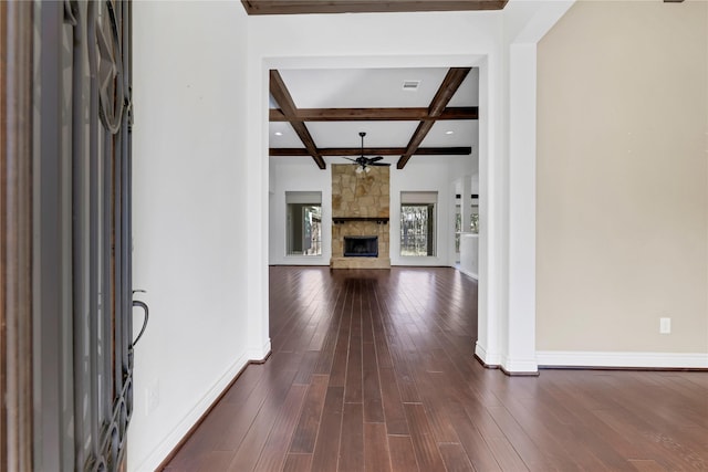 entrance foyer with ceiling fan, coffered ceiling, a stone fireplace, dark hardwood / wood-style flooring, and beamed ceiling