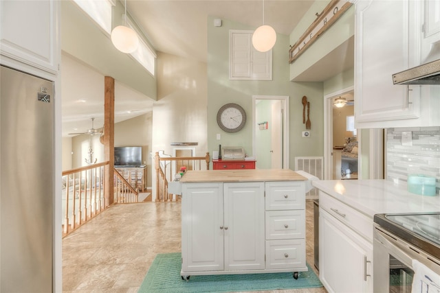 kitchen featuring stainless steel fridge, ceiling fan, pendant lighting, white cabinetry, and range hood