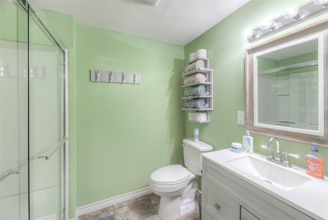 bathroom with a textured ceiling, vanity, toilet, and a shower with door