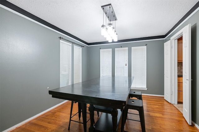 dining room featuring ornamental molding, a textured ceiling, and wood-type flooring