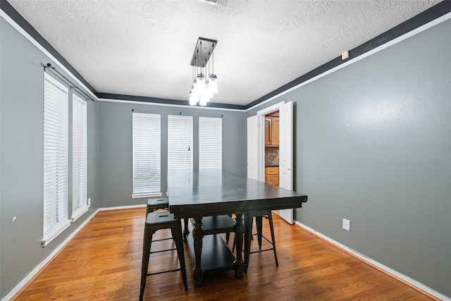 dining area featuring hardwood / wood-style floors, crown molding, and a textured ceiling