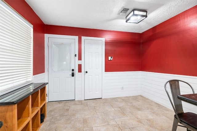 foyer entrance with wooden walls and a textured ceiling