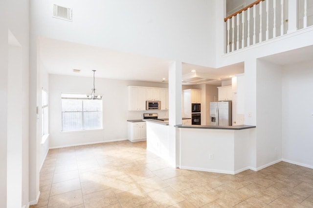 kitchen with a notable chandelier, black appliances, kitchen peninsula, decorative light fixtures, and white cabinetry