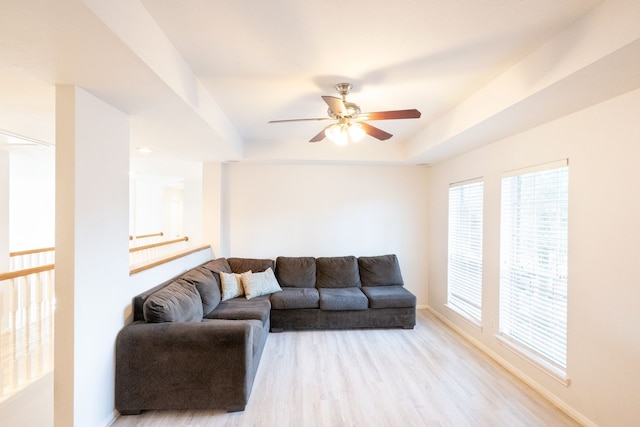 living room featuring light hardwood / wood-style floors, ceiling fan, and a tray ceiling