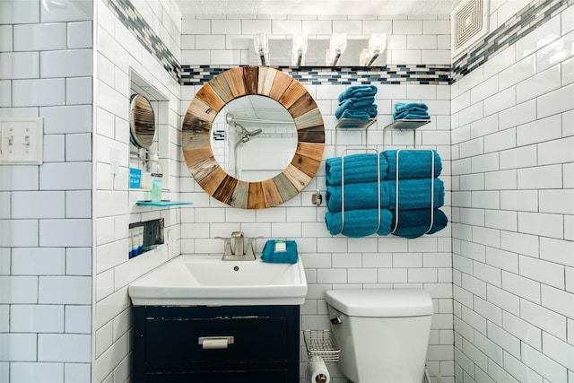 bathroom featuring vanity, toilet, and tile walls