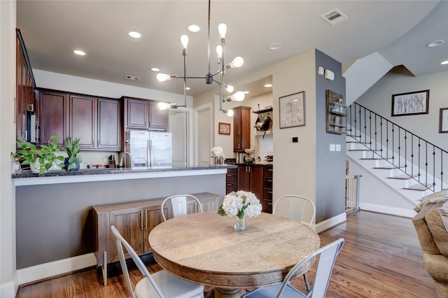 dining space with baseboards, stairs, visible vents, and wood finished floors