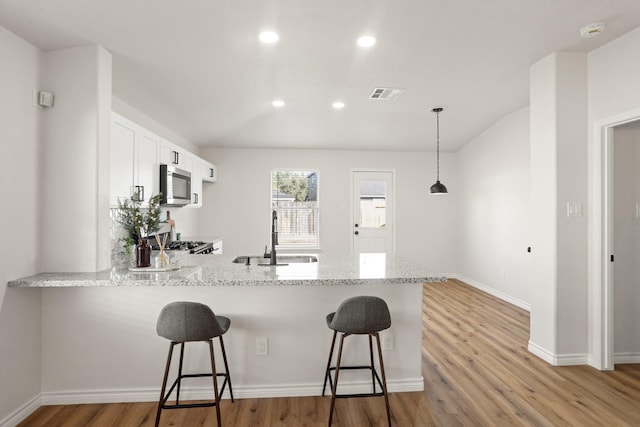 kitchen with white cabinets, a kitchen breakfast bar, sink, hanging light fixtures, and kitchen peninsula