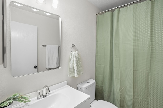 bathroom featuring vanity, a textured ceiling, and toilet