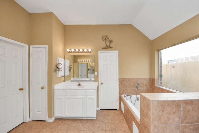 bathroom featuring tile patterned floors, vanity, lofted ceiling, and tiled tub