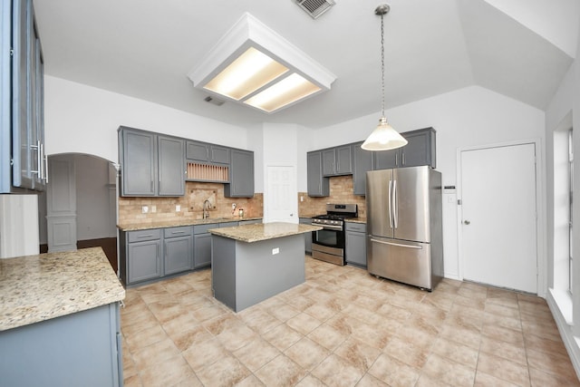 kitchen featuring a center island, hanging light fixtures, vaulted ceiling, gray cabinets, and stainless steel appliances