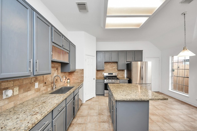 kitchen featuring sink, stainless steel appliances, pendant lighting, gray cabinets, and a kitchen island