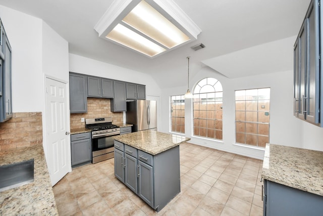 kitchen with gray cabinetry, hanging light fixtures, stainless steel appliances, light stone counters, and decorative backsplash