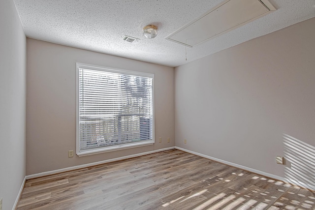 unfurnished room featuring light hardwood / wood-style floors and a textured ceiling