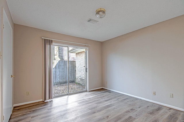 spare room featuring a textured ceiling and light hardwood / wood-style flooring