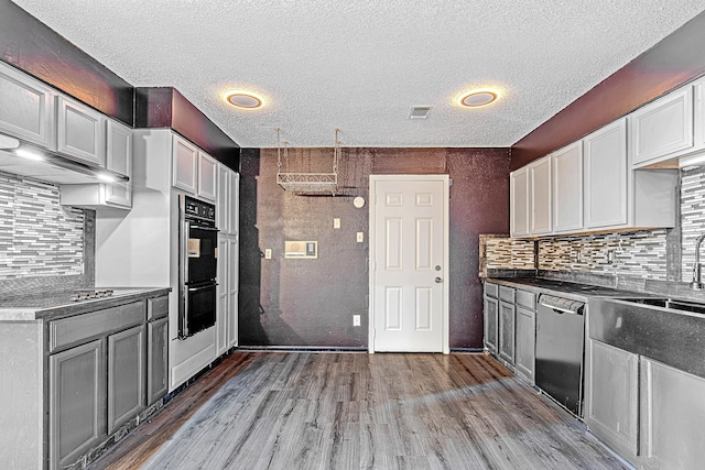 kitchen featuring backsplash, black appliances, sink, light wood-type flooring, and white cabinetry