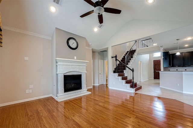 unfurnished living room with ornamental molding, vaulted ceiling, ceiling fan, a fireplace, and light hardwood / wood-style floors