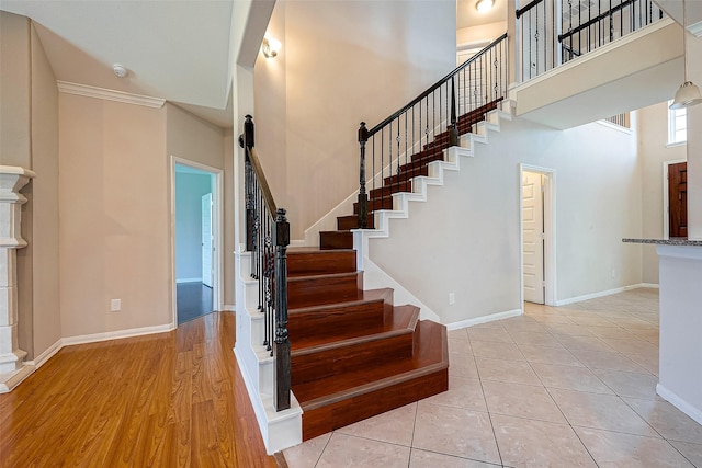 stairs featuring a towering ceiling, tile patterned floors, and ornamental molding