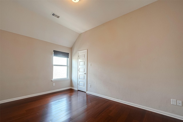 empty room featuring dark wood-type flooring and vaulted ceiling