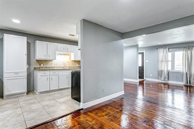 kitchen with white cabinets, light wood-type flooring, range, and tasteful backsplash