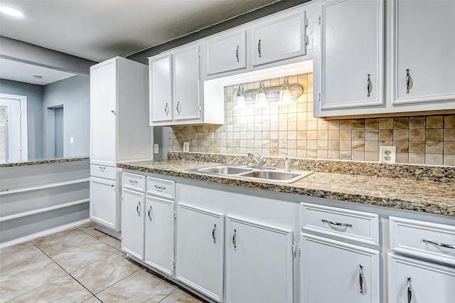 kitchen with backsplash, sink, white cabinets, and light tile patterned flooring