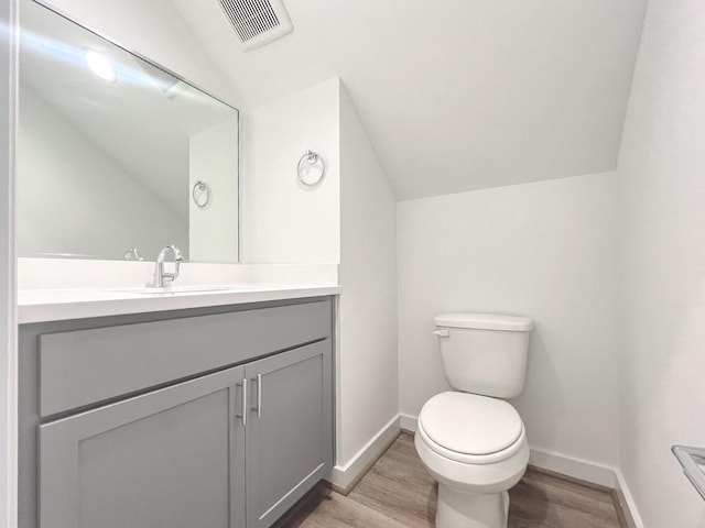 bathroom with vanity, lofted ceiling, hardwood / wood-style floors, and toilet