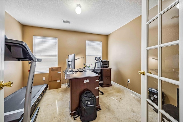 carpeted home office featuring a textured ceiling