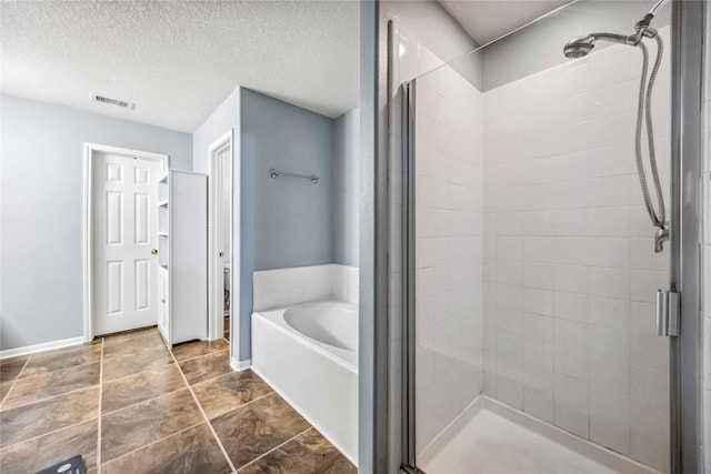 bathroom featuring separate shower and tub and a textured ceiling