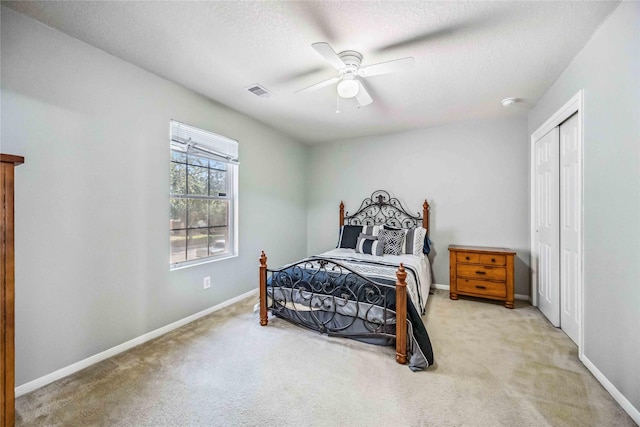 bedroom with a textured ceiling, light colored carpet, and ceiling fan