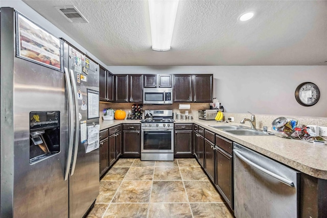 kitchen featuring a textured ceiling, sink, dark brown cabinetry, and stainless steel appliances