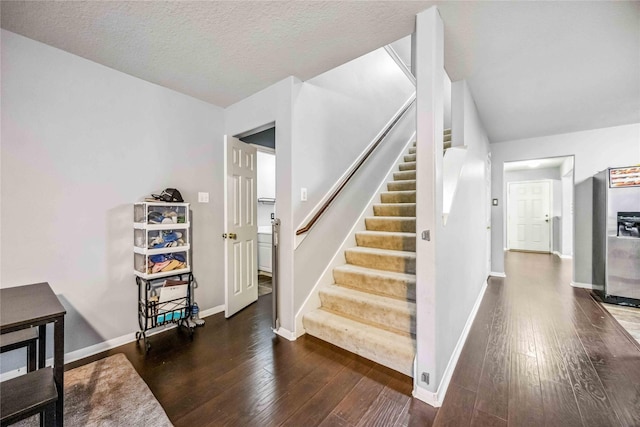 staircase with hardwood / wood-style flooring and a textured ceiling