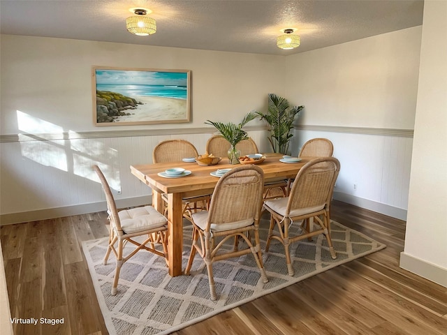 dining area featuring wood-type flooring and a textured ceiling