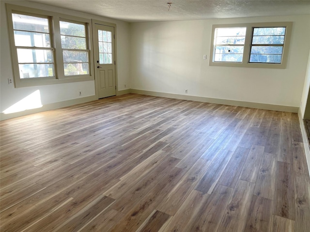 empty room featuring hardwood / wood-style floors, a healthy amount of sunlight, and a textured ceiling