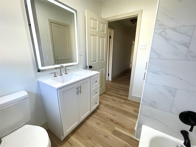 bathroom featuring hardwood / wood-style floors, vanity, toilet, and a bathing tub