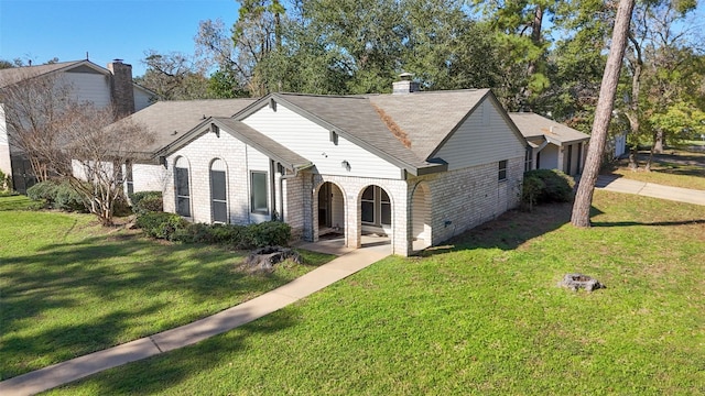 view of front of house featuring a front yard, brick siding, a chimney, and roof with shingles