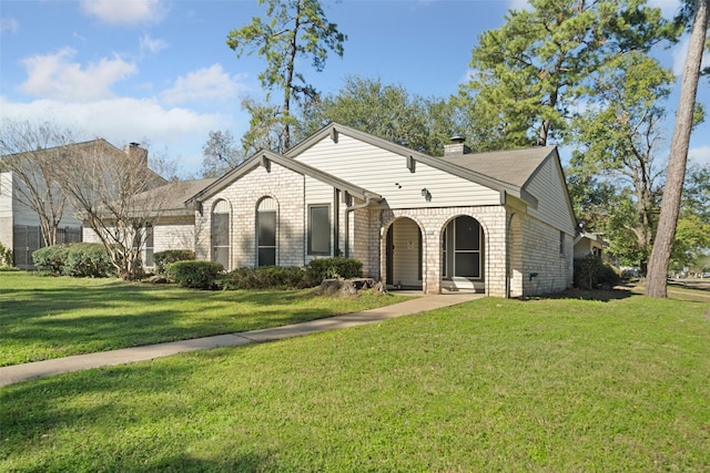 view of front of house with a front yard, brick siding, and a chimney