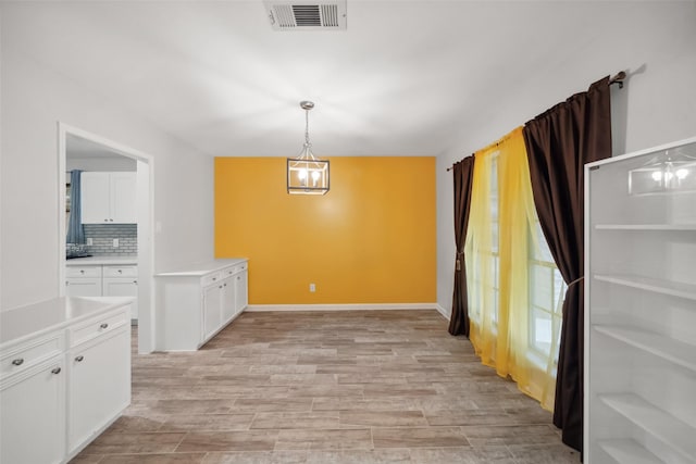 unfurnished dining area featuring light hardwood / wood-style flooring and a notable chandelier