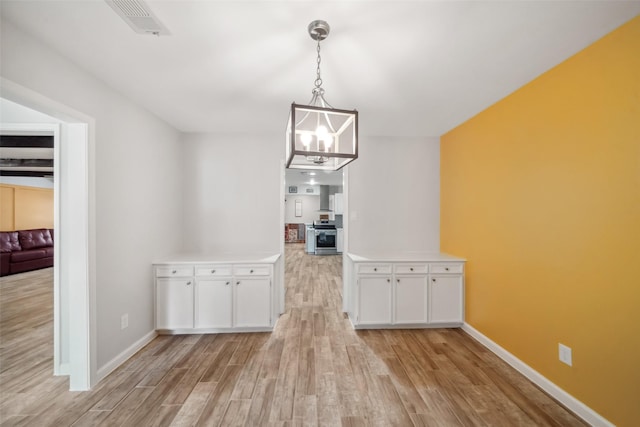 unfurnished dining area featuring light wood-type flooring and an inviting chandelier