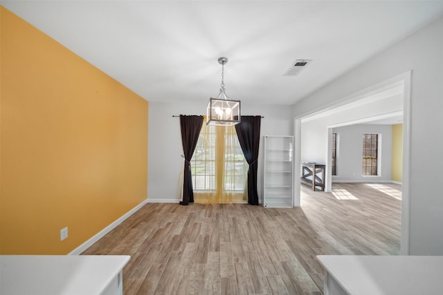 unfurnished dining area with a chandelier and light wood-type flooring