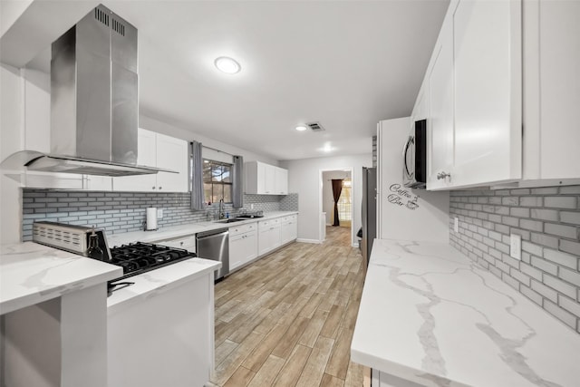 kitchen featuring light stone countertops, white cabinets, and wall chimney range hood