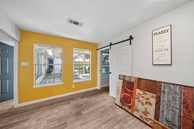 interior space with a barn door and hardwood / wood-style floors