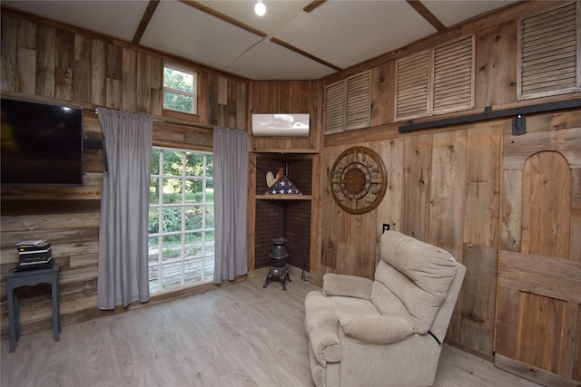 sitting room featuring wood walls, light wood-type flooring, and an AC wall unit