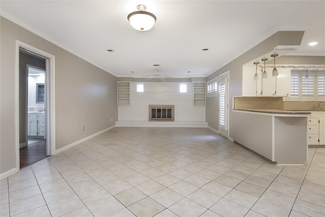 unfurnished living room featuring a fireplace, ceiling fan, light tile patterned floors, and crown molding