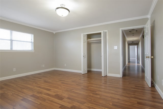 unfurnished bedroom with dark wood-type flooring, a closet, and crown molding