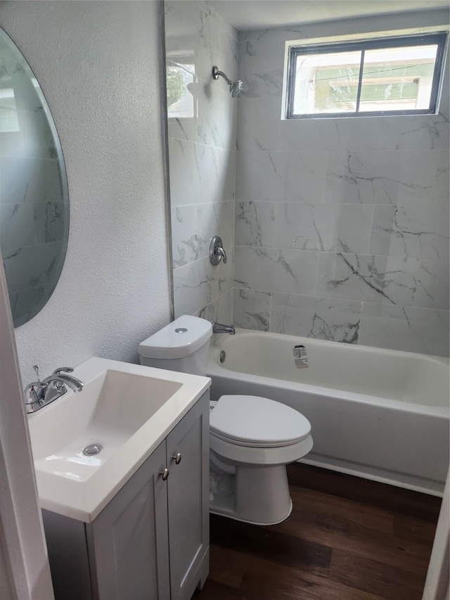 full bathroom with hardwood / wood-style floors, vanity, tiled shower / bath combo, and toilet