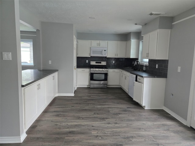 kitchen featuring sink, dark hardwood / wood-style floors, white appliances, decorative backsplash, and white cabinets