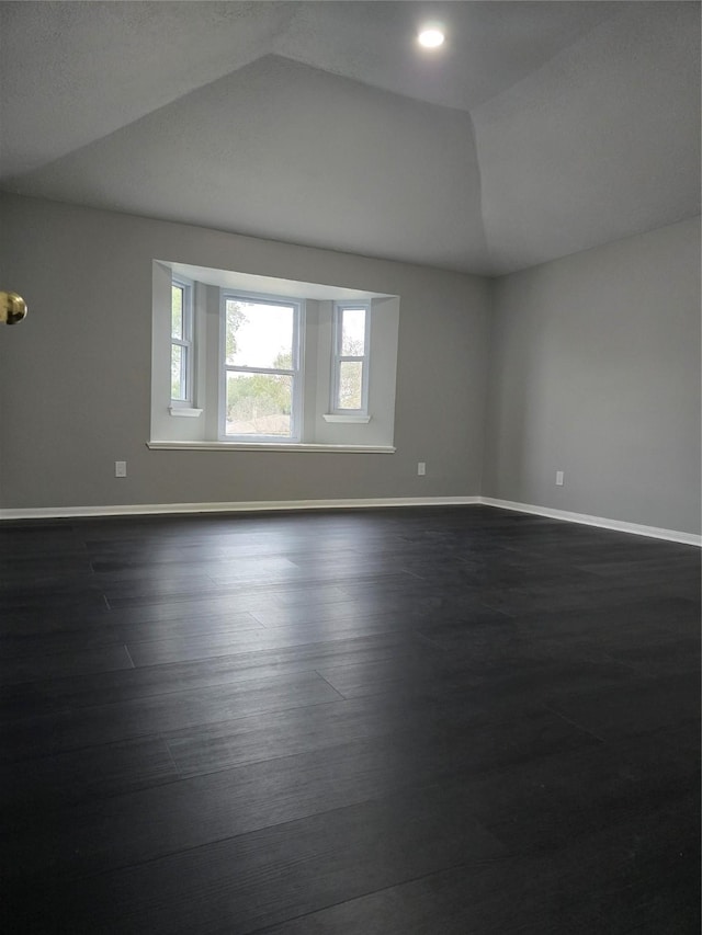 spare room featuring dark hardwood / wood-style floors and lofted ceiling